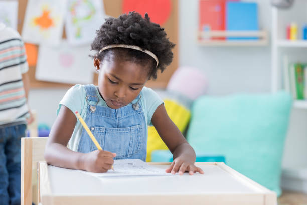 istock Young girl concentrates while drawing a picture at daycare 865903222