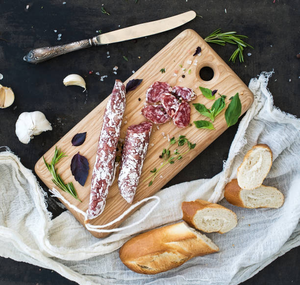 spuntino gourmet di carne. salame, aglio, baguette ed erbe aromatiche su tavola rustica in legno - dry cured ham foto e immagini stock