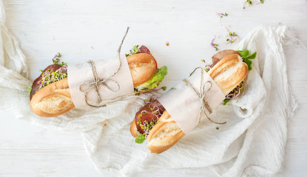 Sandwiches with beef, fresh vegetables and herbs over white wood backdrop