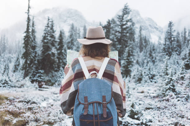 Young traveling woman enjoying first snow and looking at the map stock photo