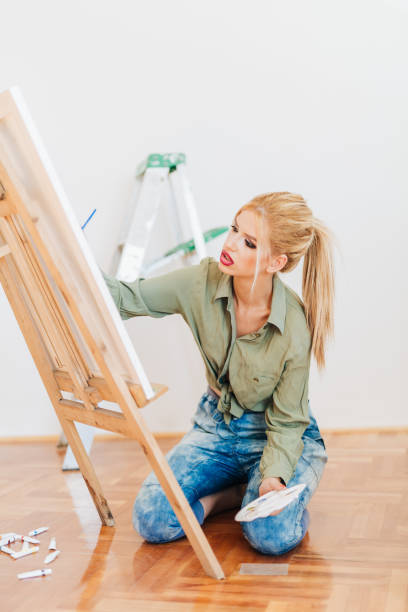 istock Young blond woman painting with brush on a canvas 865928190
