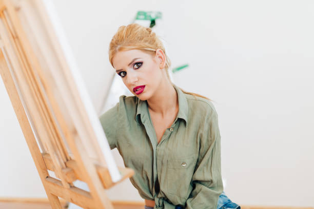 istock Young blond woman painting with brush on a canvas 865928526