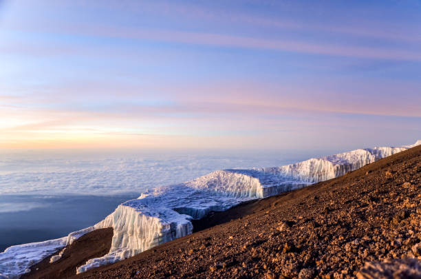 nascer do sol, próximo do cume do monte kilimanjaro (montanha mais alta da áfrica no amdt 5895m), na tanzânia. bela vista das partes restantes do glaciar chamado campo de gelo sul em primeiro plano. - 5895 - fotografias e filmes do acervo