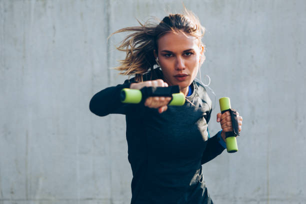 Young woman training with dumbbells Young woman training with dumbbells in an urban scene. women boxing sport exercising stock pictures, royalty-free photos & images