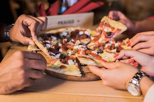 Young group of people enjoying pizza. Hand close-up.