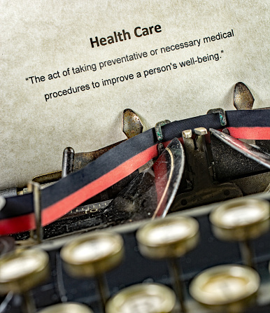 Typewriter with the definition for Health Care. Shown to be written on an antique typewriter
