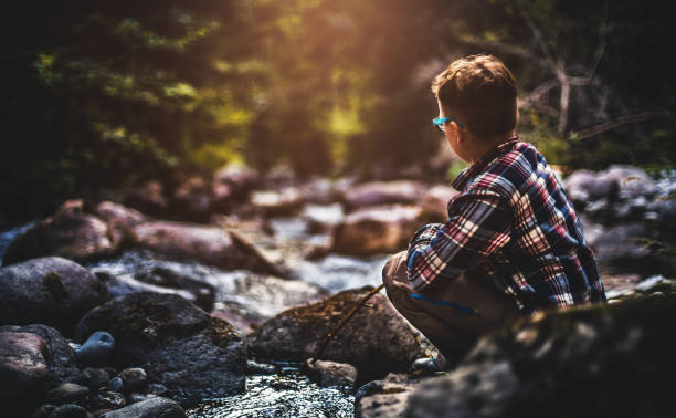 istock A boy sitting near water stream and watching forward 865938776