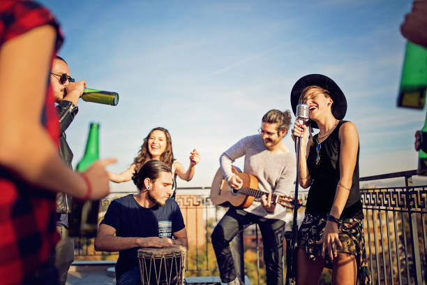Group of friends are celebrating with a concert on the roof terrace Group of friends are celebrating with a concert on the roof terrace performance group stock pictures, royalty-free photos & images