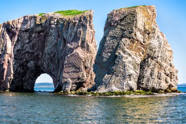 Rocher Perce rock in Gaspe Peninsula, Quebec, Gaspesie region with birds and cliffs during day