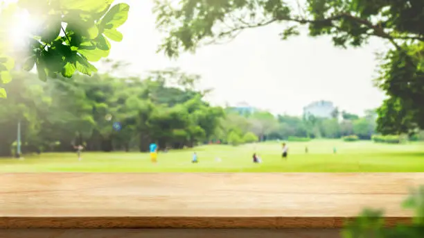 Empty wood table top with blur park green nature bokeh and leaf foreground,Mock up for display or montage of product,Banner or header for advertise on social media,Spring and Summer background.