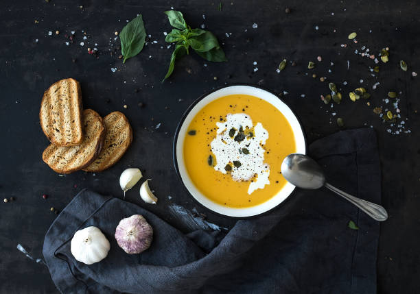 istock Pumpkin soup with cream, seeds, bread and fresh basil on grunge black background 865962206