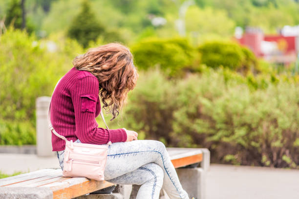 One young happy woman sitting on bench on sidewalk in green downtown city park in Saguenay, Canada, Quebec during summer looking at phone or reading book One young happy woman sitting on bench on sidewalk in green downtown city park in Saguenay, Canada, Quebec during summer looking at phone or reading book 4810 stock pictures, royalty-free photos & images