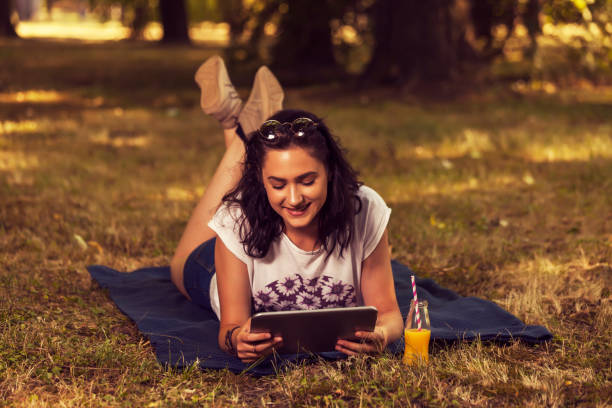 istock Teenage girl lying on a blanket in nature and using a tablet 865963230