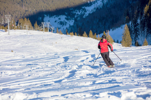 Skier skiing downhill in high mountains against sunset.