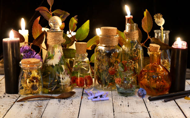 istock Glass bottles with potions, herbs and black candle on table 865967520