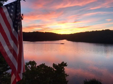Sunset on lake with fishing boat and American flag