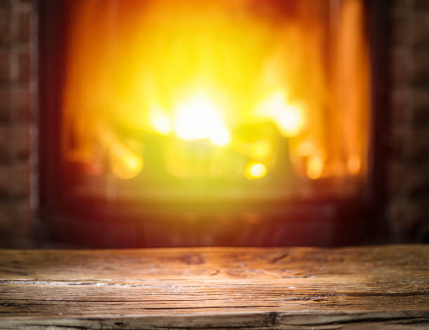 istock Old wooden table and fireplace with warm fire on the background. 866018282