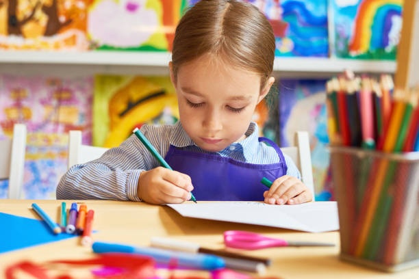 Little Girl Drawing in Pre-School Portrait of adorable little girl  drawing pictures during art and craft class in pre-school one boy only photos stock pictures, royalty-free photos & images