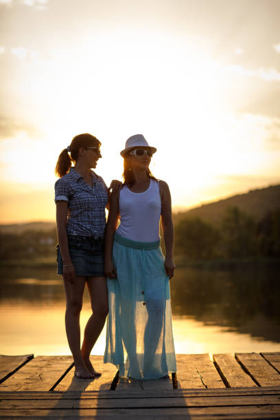 istock Sisters enjoying sunset on lake pier 866035694