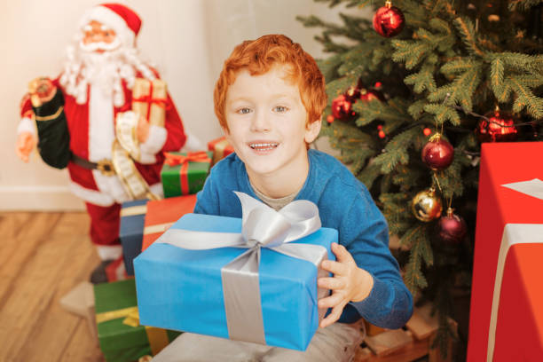 Excited Redhead Kid Smiling While Holding His Christmas Present