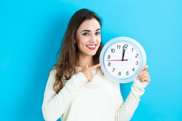 istock Woman holding clock showing nearly 12 866039616