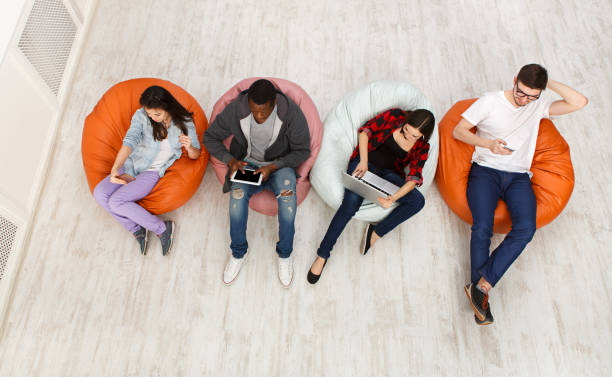 istock Friends using gadgets, sitting indoors in line 866039662