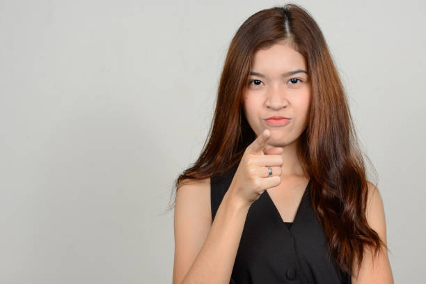 Studio shot of young beautiful Asian woman against white background