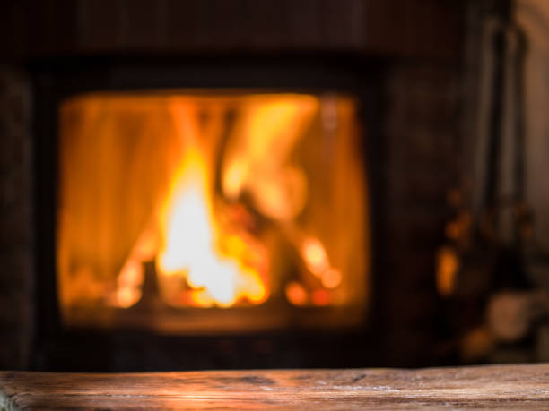 istock Old wooden table and fireplace with warm fire on the background. 866046698