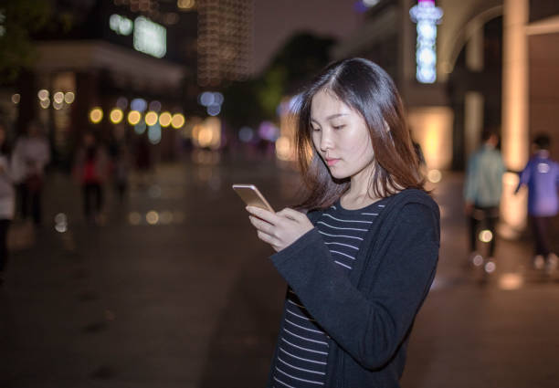 istock woman using smartphone on street at night 866049134
