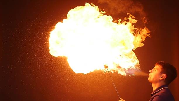 istock Fire show performance. A man picks gasoline at a torch, slow motion 866049552