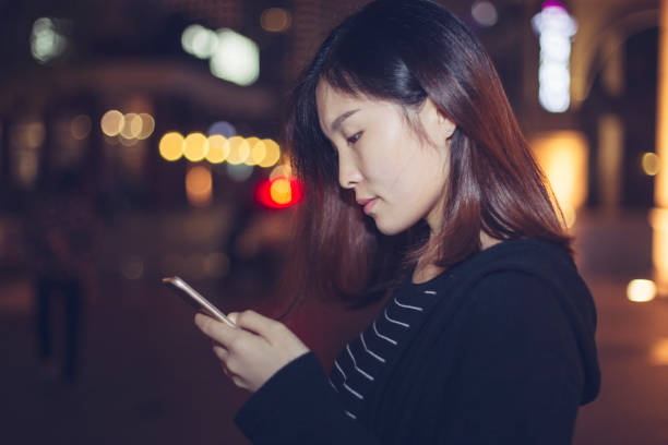 istock woman using smartphone on street at night 866049594