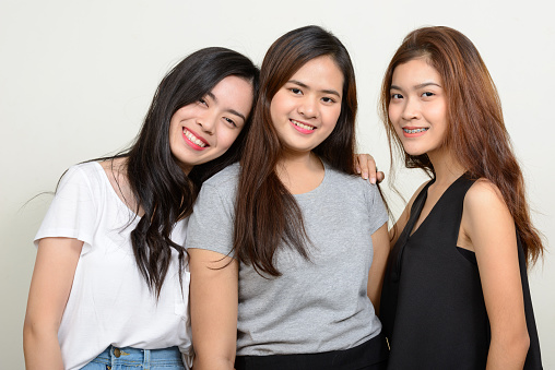 Studio shot of young beautiful Asian woman friends against white background