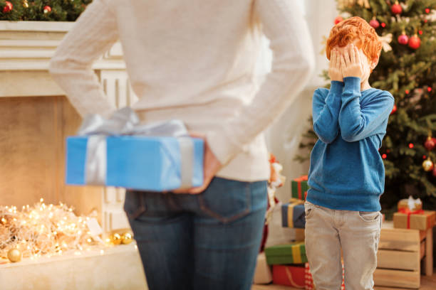 istock Excited boy closing his eyes while waiting for christmas present 866058390