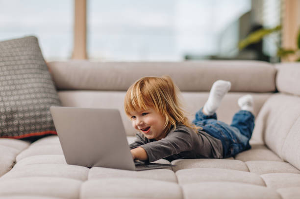 istock Cute boy relaxing on sofa at home and using laptop. 866059264