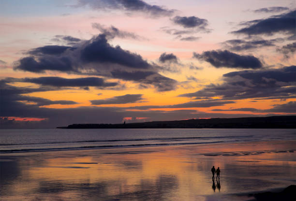 istock Romantic scene, a Couple walking on the beach at Sunset 866072460