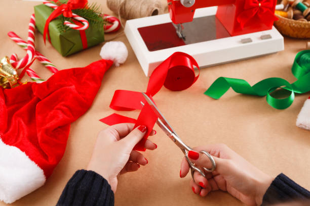 istock Female hands with scissors cutting red ribbon. Xmas diy 866073184