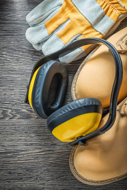 istock Protective gloves waterproof working boots earmuffs on wooden bo 866073222