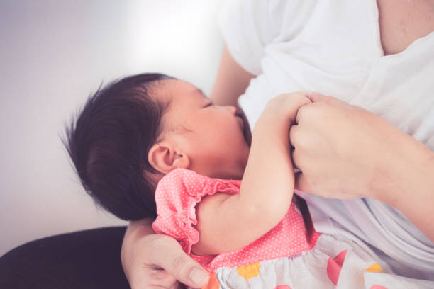 primo piano sulla mano della madre che tiene la mano del bambino mentre la madre allatta la sua bambina appena nata - sucking asian ethnicity baby mother foto e immagini stock