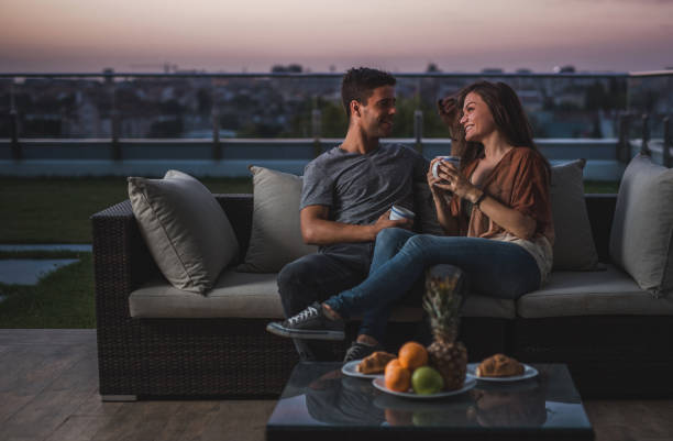 istock Young couple in love drinking coffee on a patio at dawn and talking. 866079492