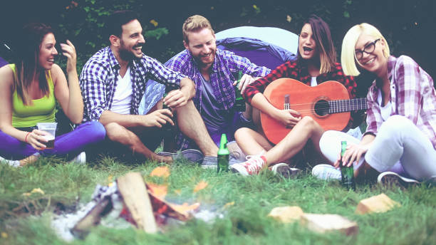 istock Five friends sitting next to campfire and singing song 866080062
