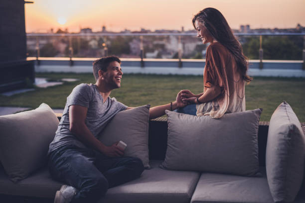 istock Happy couple holding hands and communicating on a terrace at sunrise. 866080202