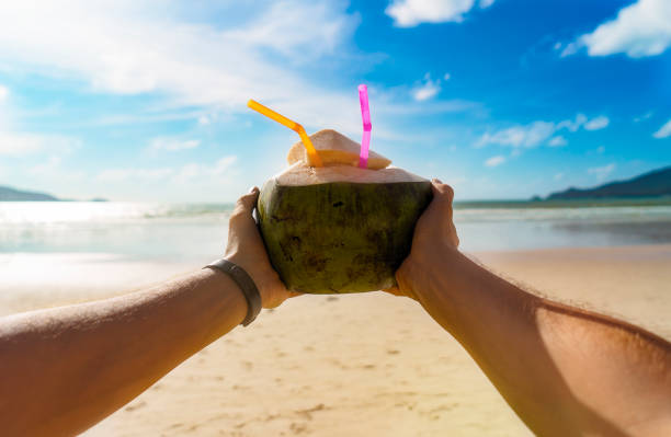 mann, der eine kokosnuss in patong beach - strand patong stock-fotos und bilder