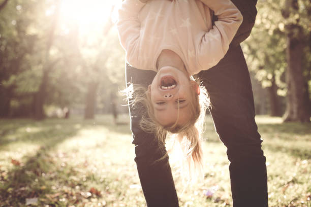 istock Father holds his daughter's feet. Girl hangs upside down. 866094832