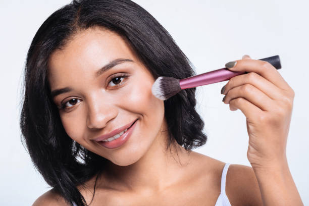 istock Cheerful young woman using powder brush 866096734