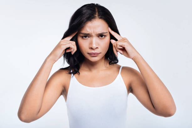 istock Dark-haired young woman pressing fingers to temples 866097026