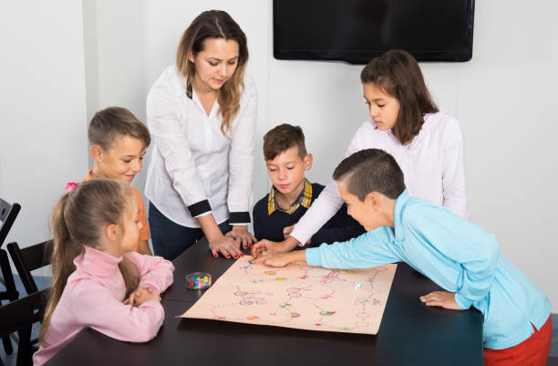 istock Elementary age satisfied children at table with board game and dice 866099792
