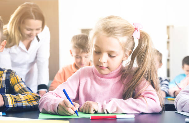 istock Teacher and elementary age children drawing at classroom 866099870