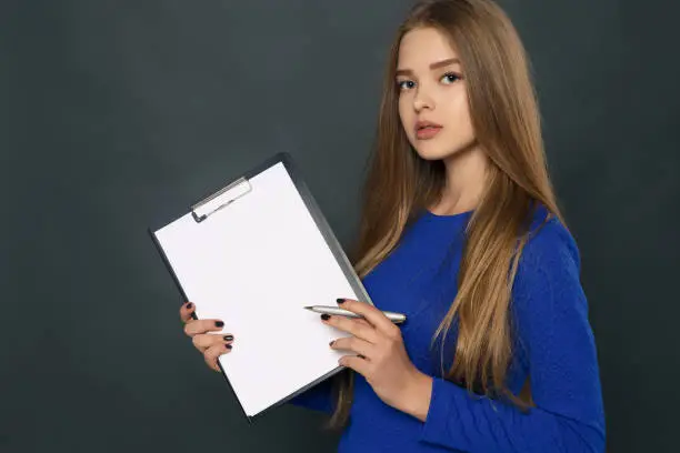Young girl in a blue dress, holds contract and handle for signing. Insurance policy, bank credit. Copy space