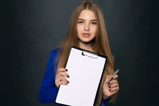 Young girl in a blue dress, holds contract and handle for signing. Insurance policy. Copy space