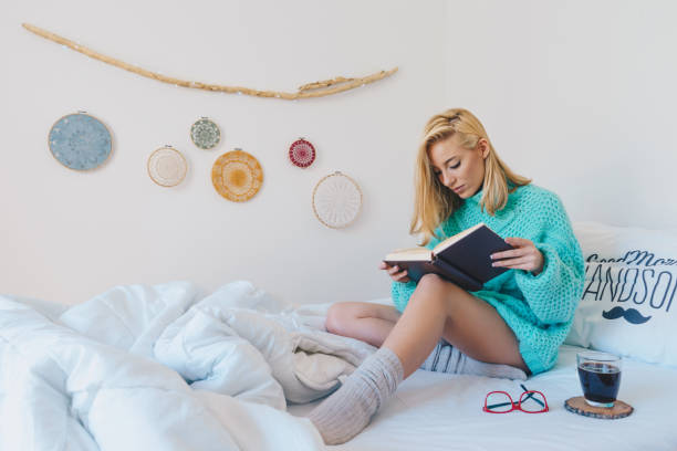 istock Young woman sitting in bed while reading a book 866120378